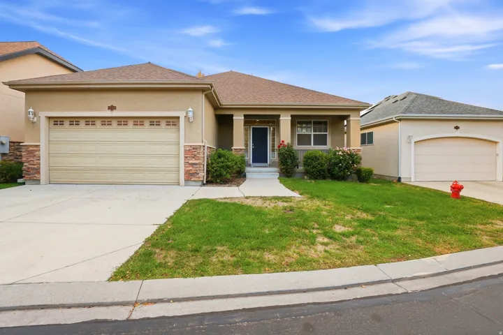Stucco exterior with stone accents, covered front porch, and an attached two-car garage