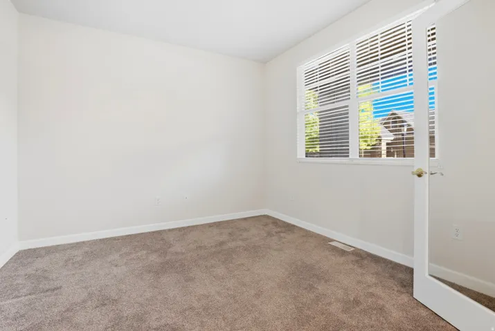Neutral-toned carpeting, ample natural light, white trim, and a window with horizontal blinds