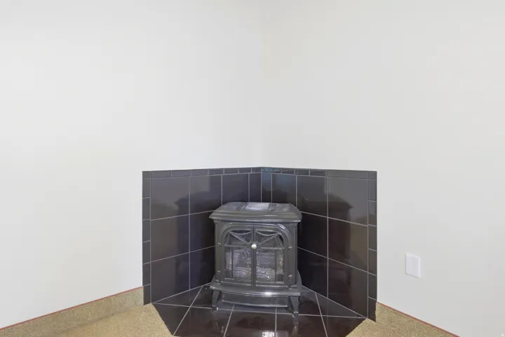 Corner wood-burning stove with a black tile surround