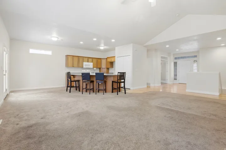 Recessed lighting, wood-finish cabinetry, white kitchen appliances, light wood-finish flooring, and vaulted ceiling