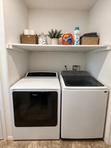 Built-in laundry closet featuring a white shelf and wood-finish flooring