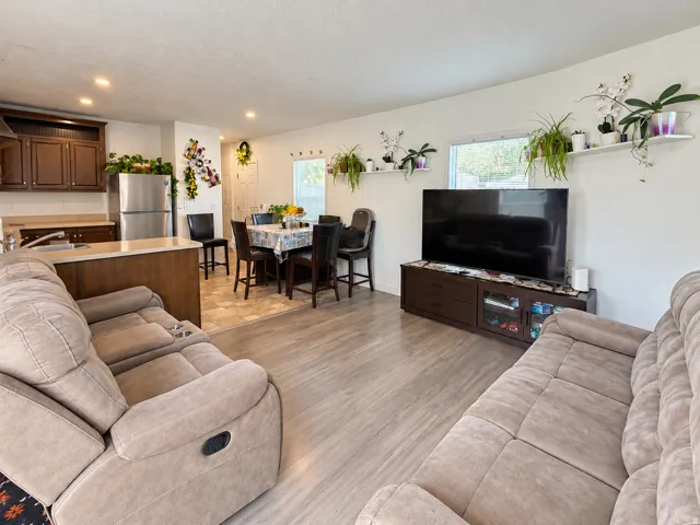 Open-concept living space featuring wood-finish flooring, recessed lighting, and a kitchen with wood cabinetry, stainless steel appliances, and a breakfast bar