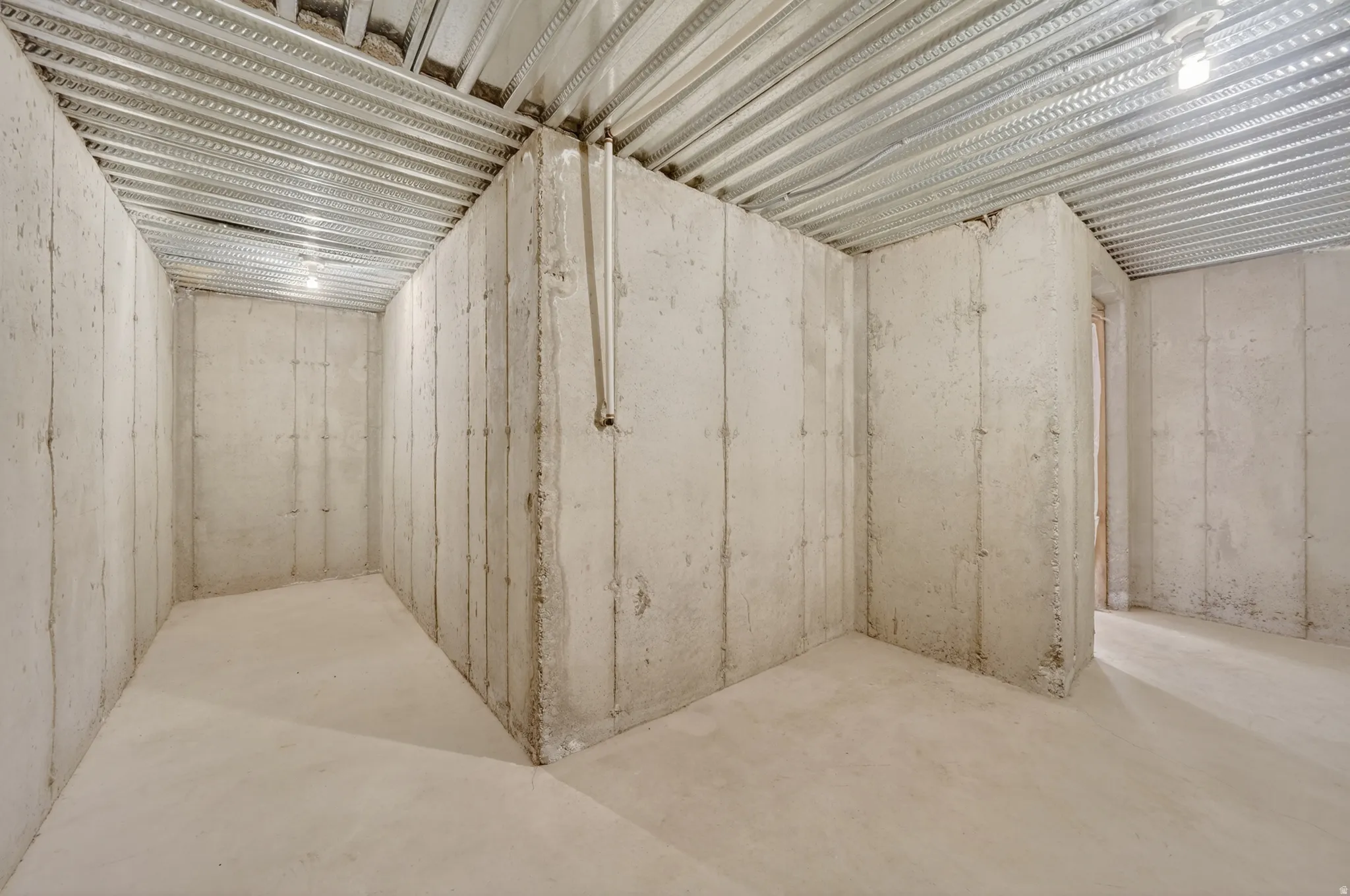 Unfinished basement with concrete walls, concrete flooring, and exposed metal ceiling joists
