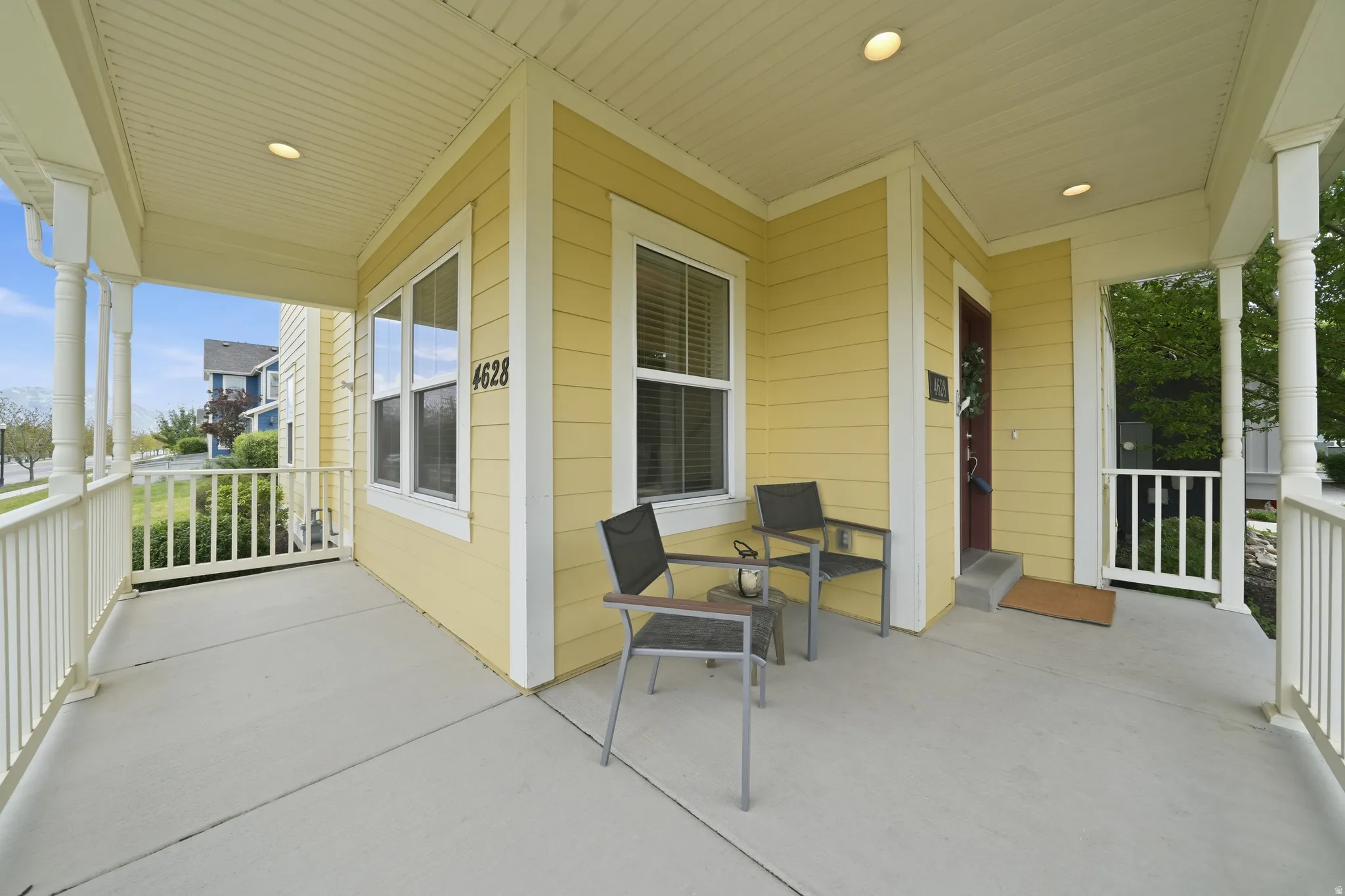 Covered porch with concrete flooring, white railing, and recessed lighting