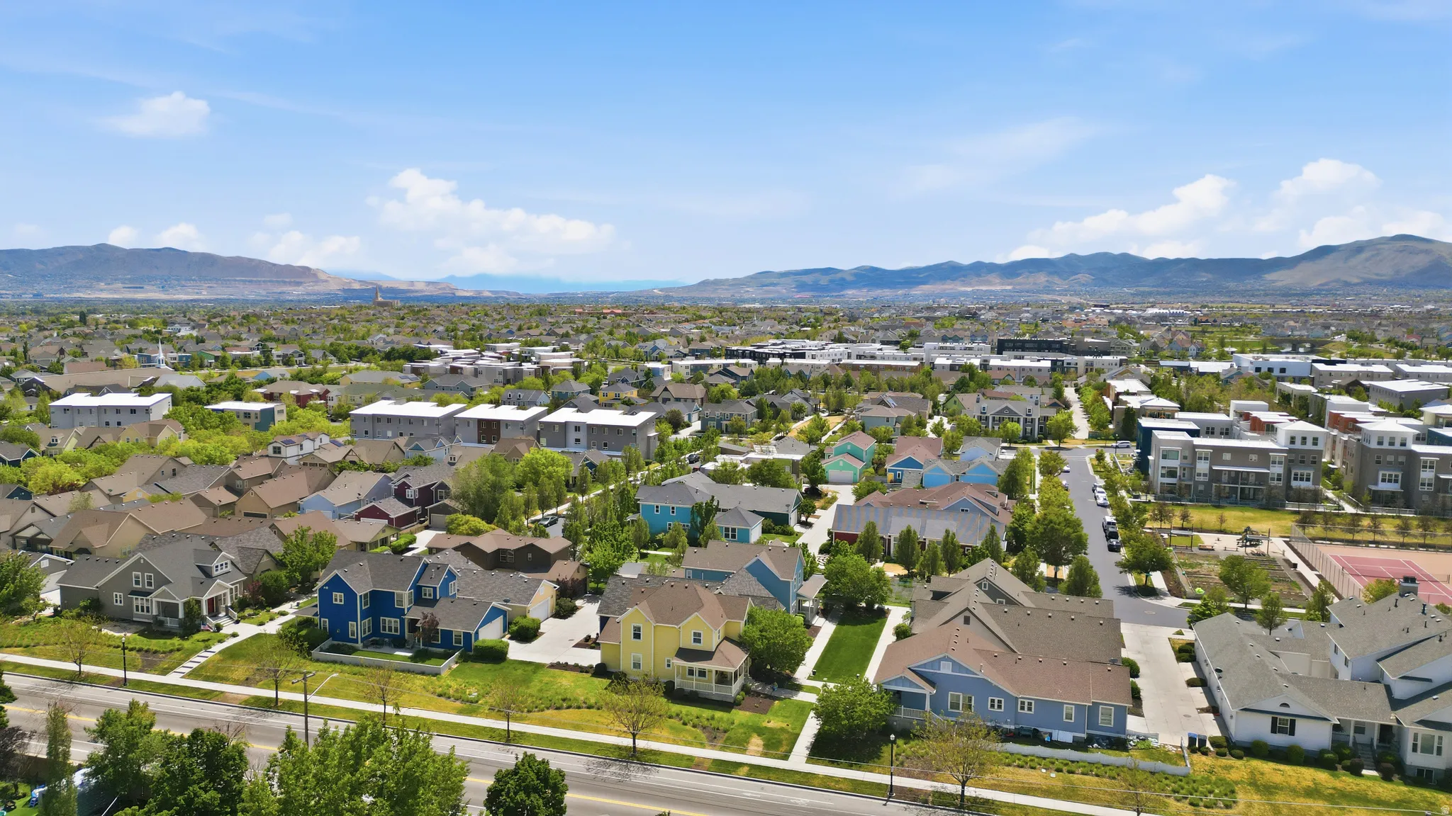 Expansive residential area featuring a variety of architectural styles, mature trees, and a distant mountain range