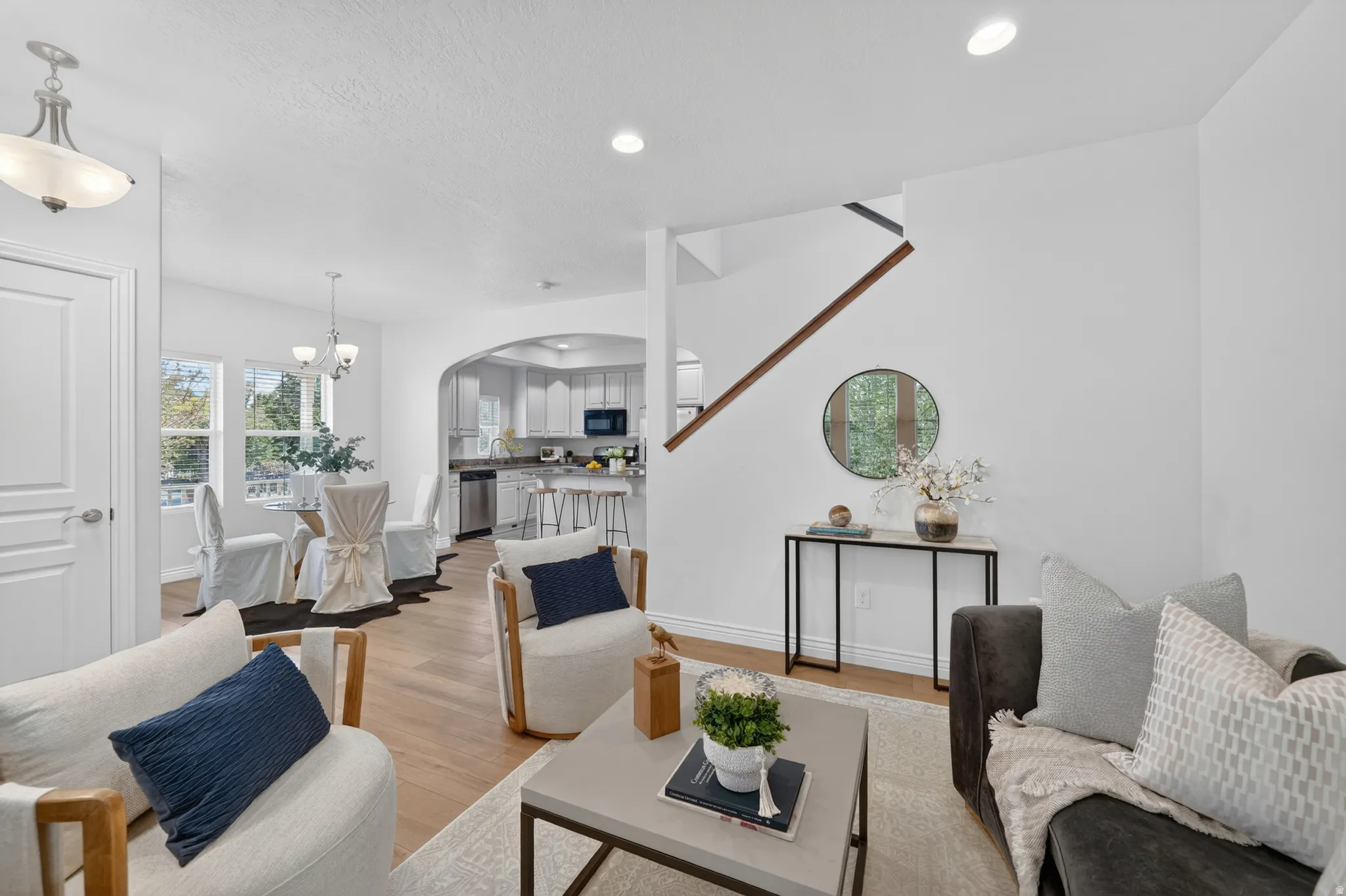 Recessed lighting, wood-finish flooring, staircase with wood handrail, an arched doorway, and built-in kitchen cabinetry