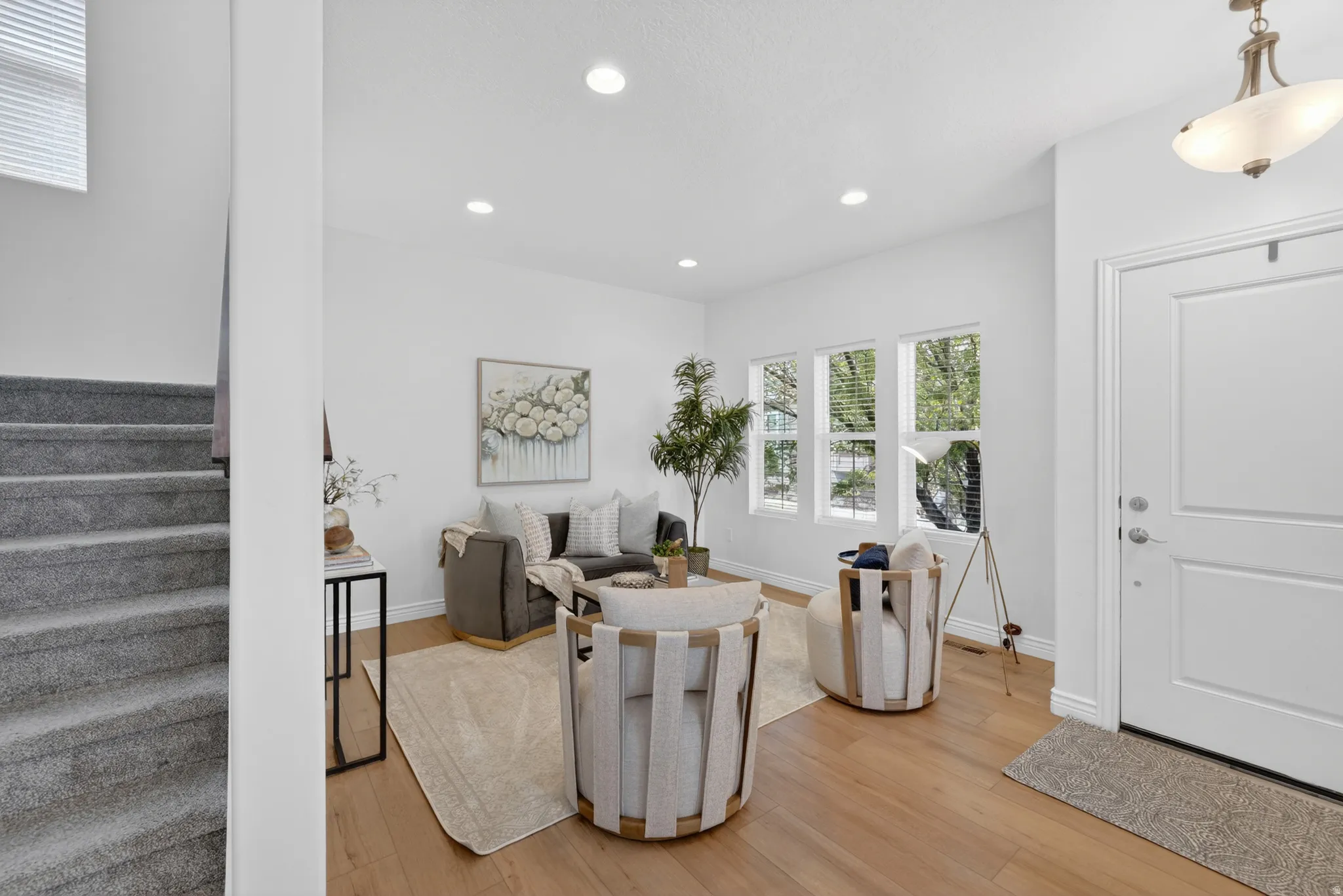 Recessed lighting illuminates the living space with wood-finish flooring