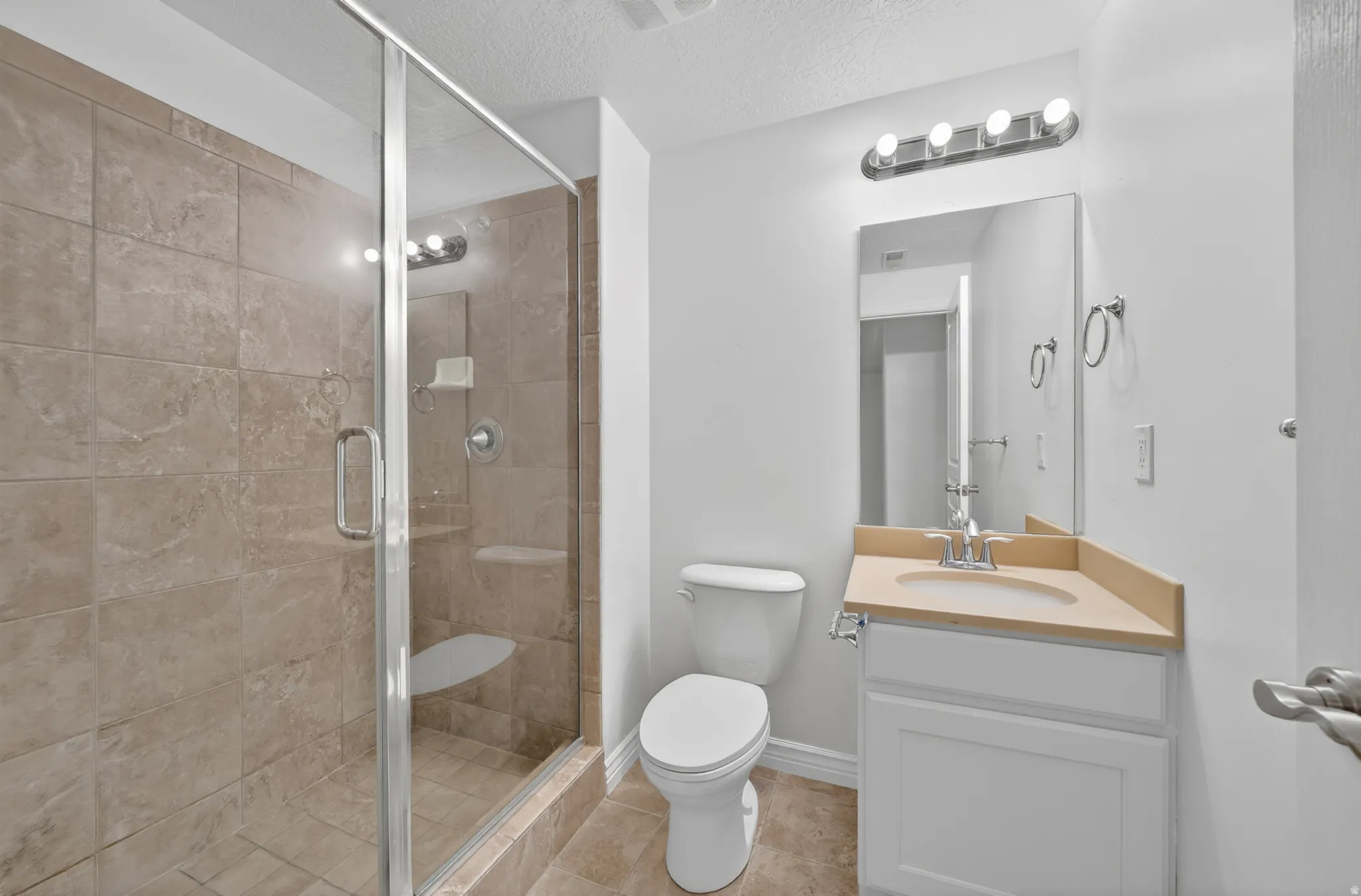 Walk-in shower with glass enclosure, integrated shower bench, and neutral-toned tile surround