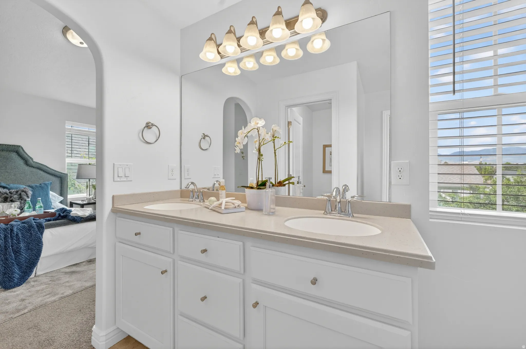Dual vanity with integrated sinks and brushed nickel faucets, set against a large mirror with overhead sconce lighting