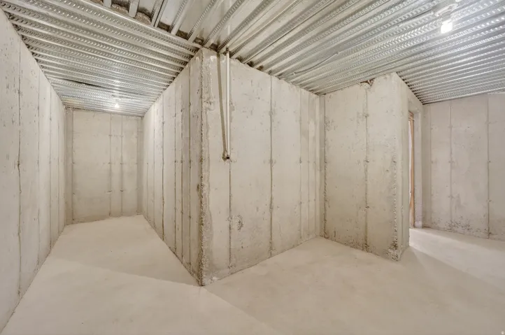 Unfinished basement with concrete walls, concrete flooring, and exposed metal ceiling joists