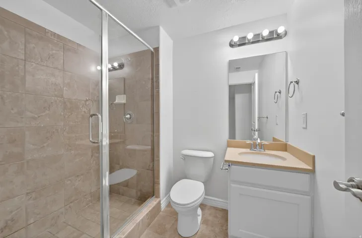 Walk-in shower with glass enclosure, integrated shower bench, and neutral-toned tile surround