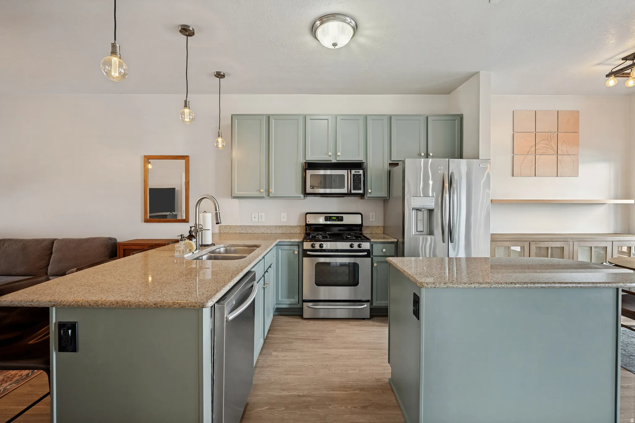 Kitchen featuring light blue cabinetry, stainless steel appliances, granite countertops, and wood-finish flooring