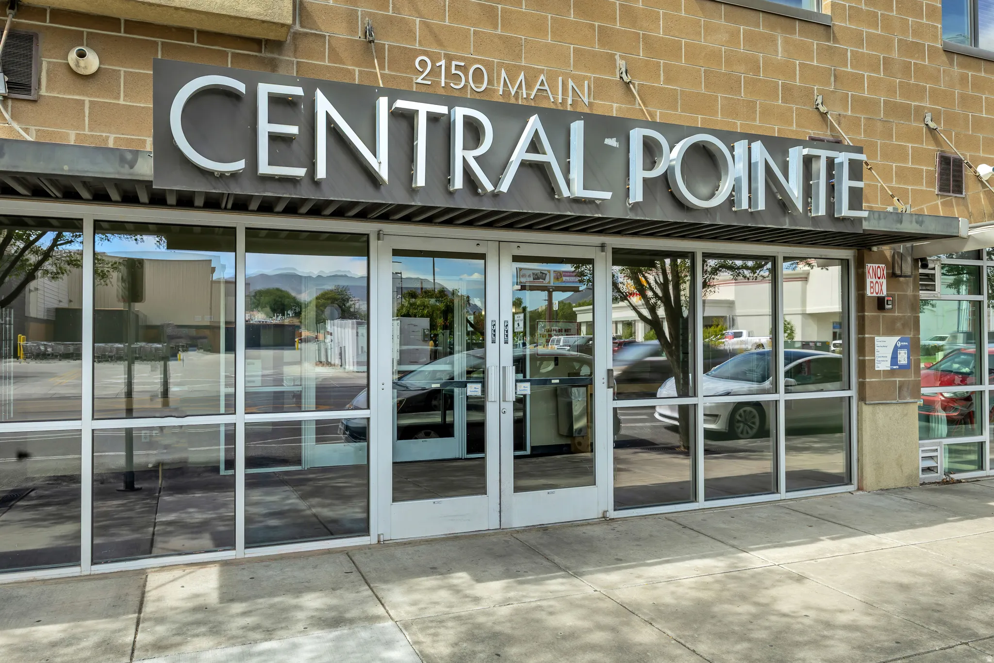 Building exterior featuring brick construction, prominent signage, a metal awning, and multiple large storefront windows