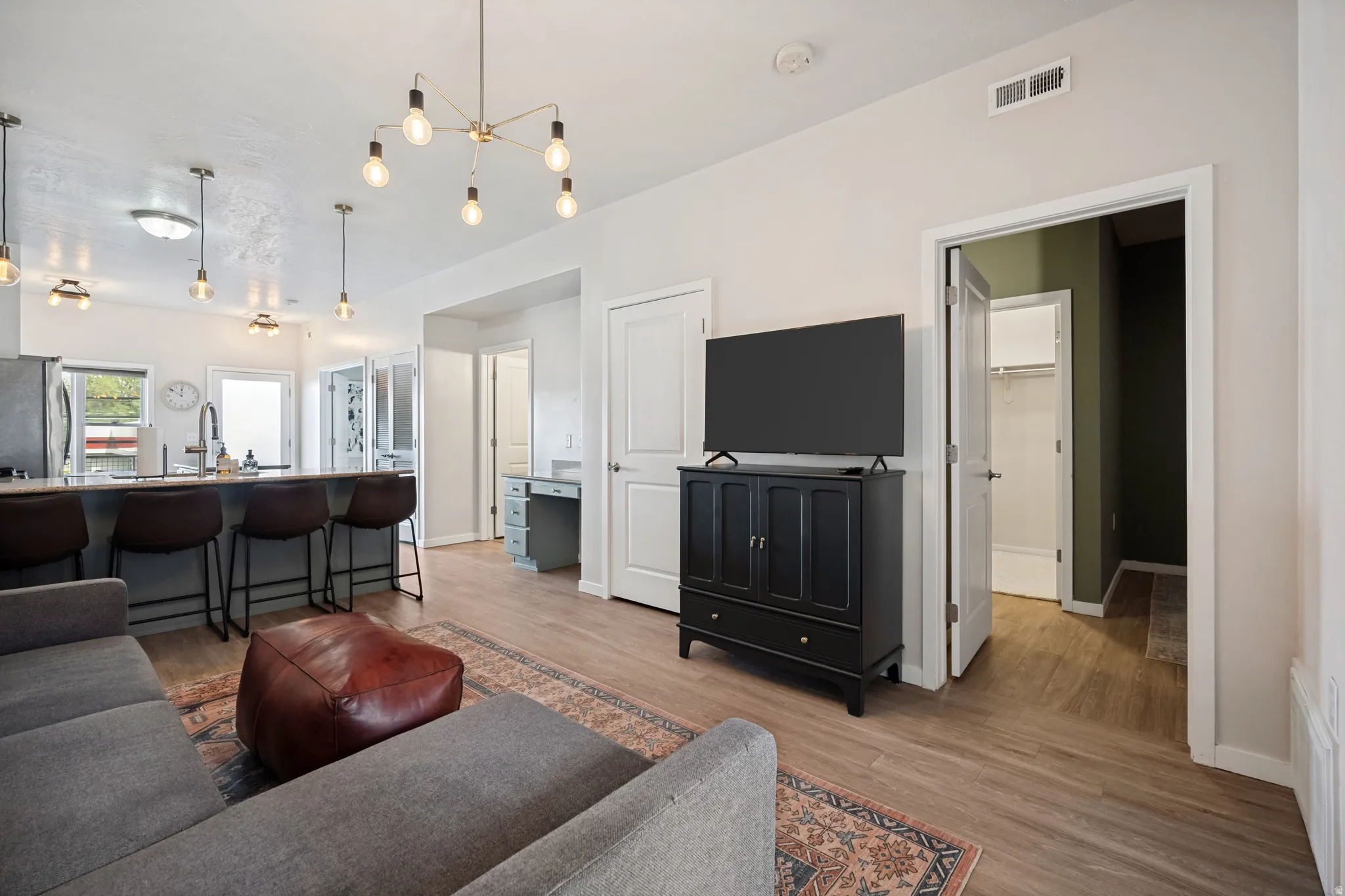Open-concept living space featuring wood-finish flooring, a contemporary chandelier, and a built-in desk area
