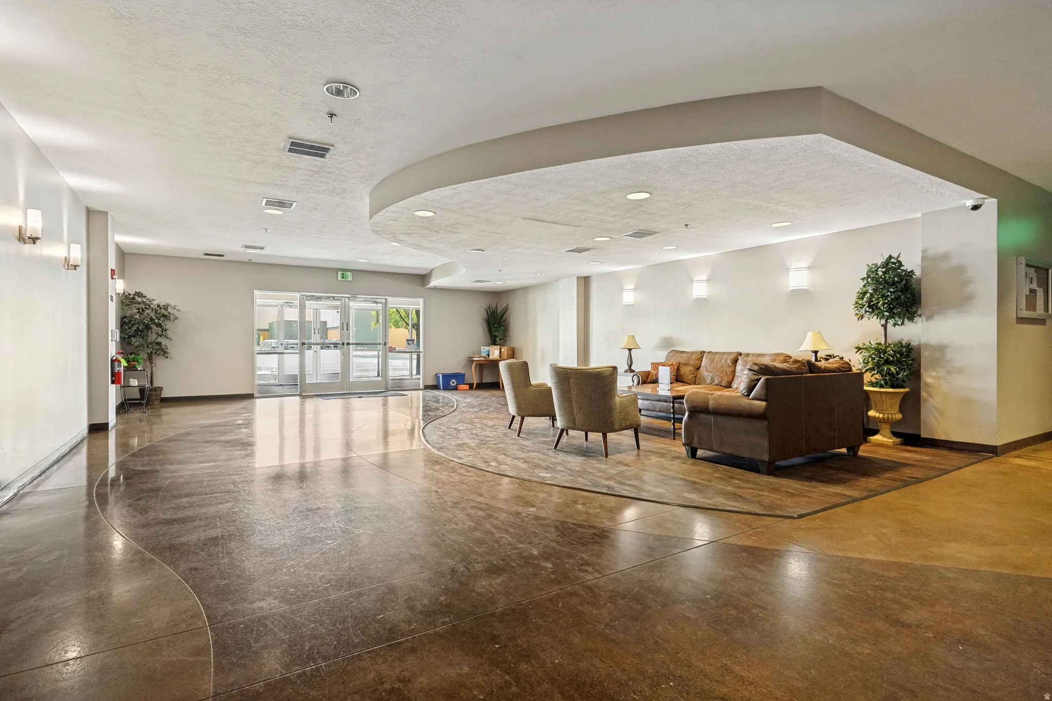 Expansive common area featuring a curved ceiling detail, recessed lighting, and glass entry doors