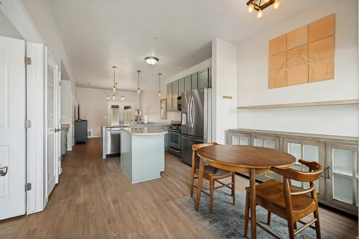 Open-concept living space with wood-finish flooring, a kitchen island, stainless steel appliances, and a built-in buffet