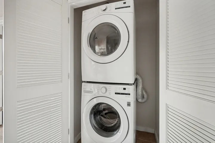 Stacked laundry appliances within a dedicated closet, featuring louvered bi-fold doors