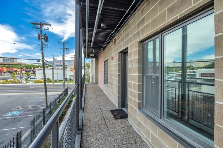 Exterior hallway with concrete block walls, large glass windows, and metal railings