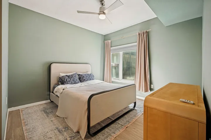 Wood-finish flooring, recessed lighting, ceiling fan, window with curtains, and neutral wall tones