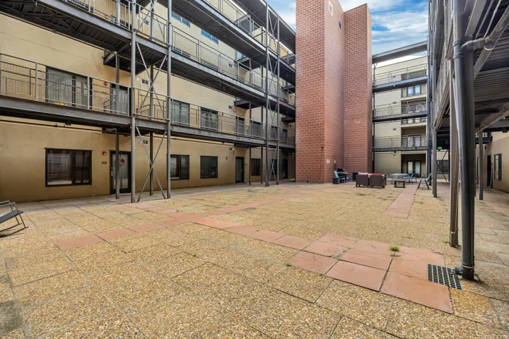 Central courtyard with aggregate and paver flooring, featuring multi-level open-air walkways with metal railings