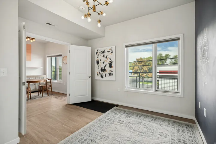 Hardwood-style flooring throughout, modern light fixture, and large window with exterior fencing