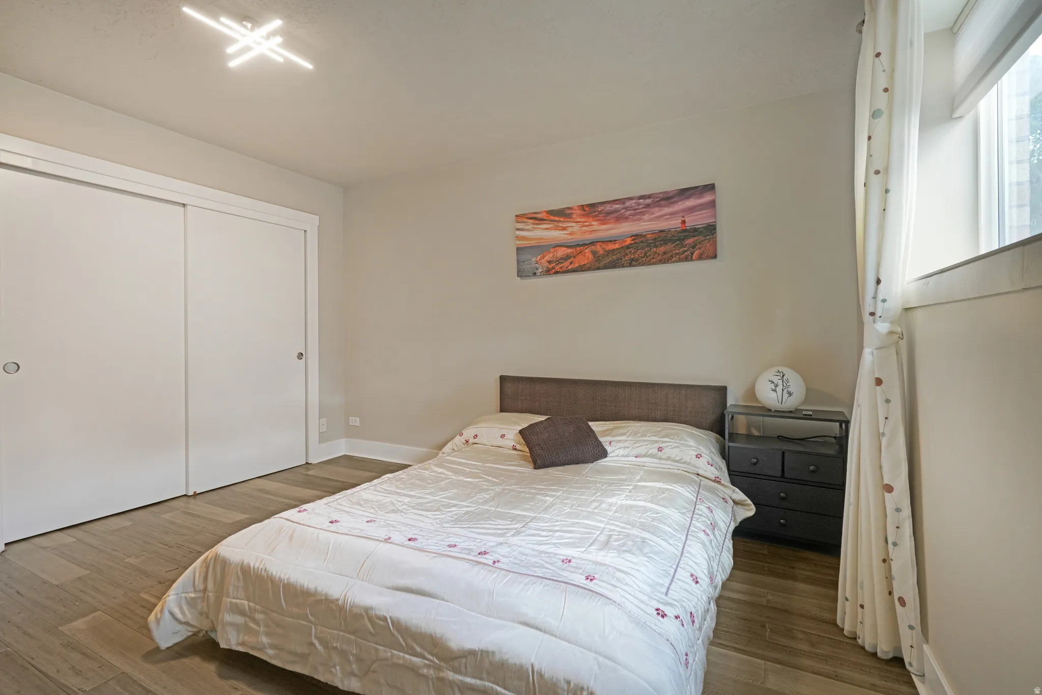 Sliding closet doors, wood-finish flooring, modern ceiling light fixture, window with trim