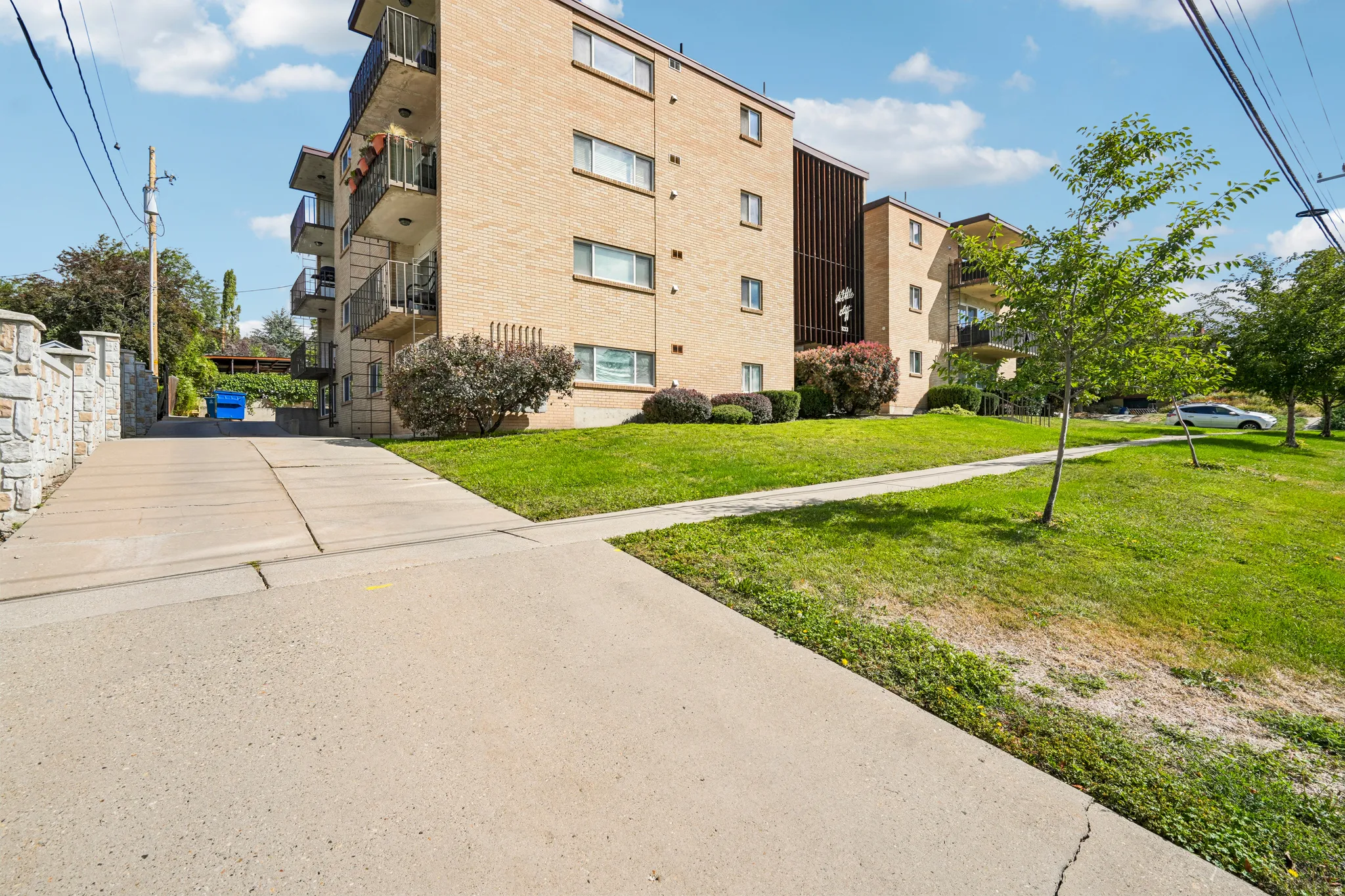 Brick exterior building with multiple private balconies and a paved concrete driveway