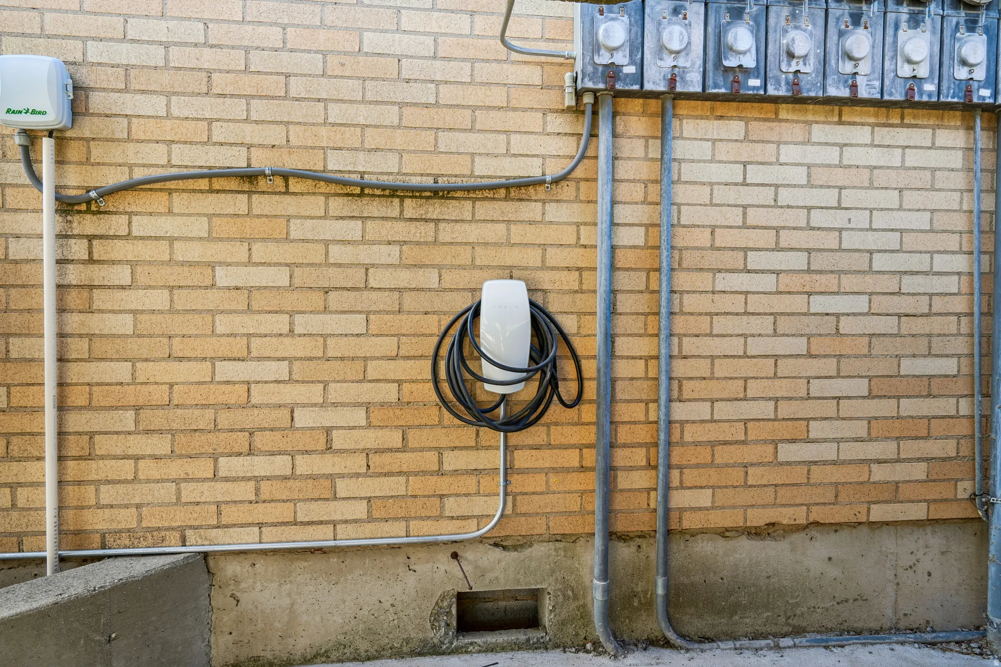 Brick exterior featuring an EV charger, irrigation system controller, and multiple utility meters
