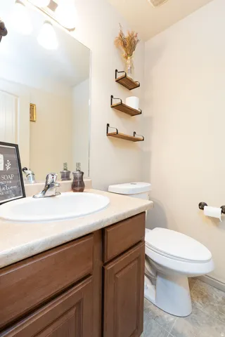 Vanity with wood-finish cabinetry, integrated sink, and light-toned countertop