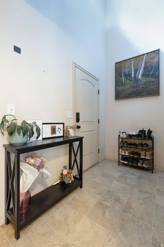 Vaulted ceiling, arched interior door, modern door hardware, wall-mounted light switch, and square tile flooring