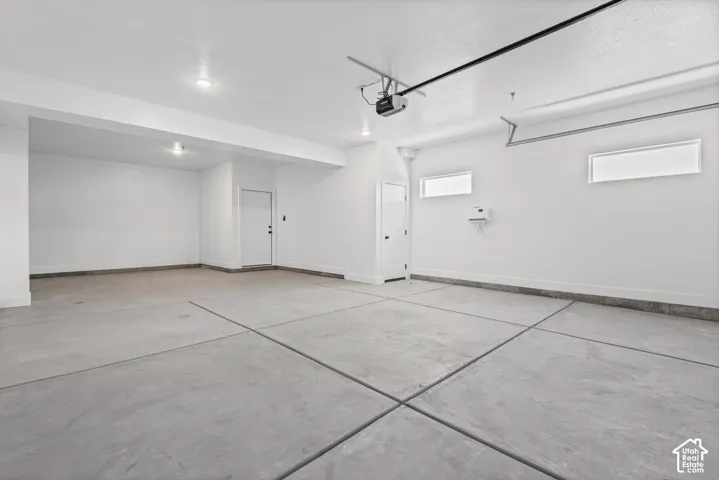 Clean concrete flooring, bright white walls, recessed ceiling lights, and two horizontal windows