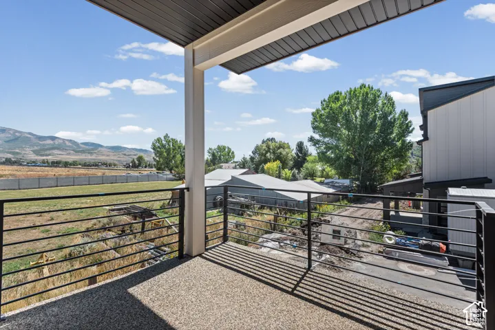 Balcony featuring a speckled concrete surface, black horizontal railing, and an overhead support column