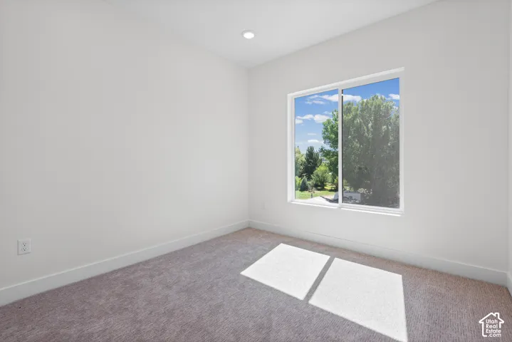 Recessed ceiling lighting, a large window, white walls, and gray carpet