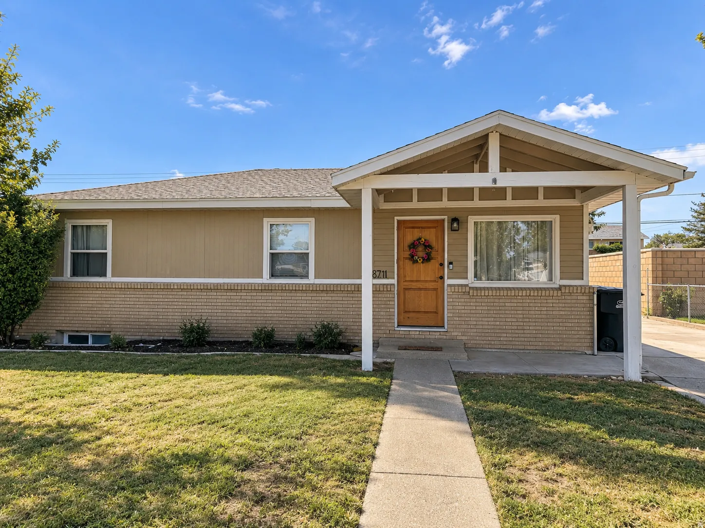 Exterior featuring a brick facade, covered entry, wood-finish front door, and concrete walkway