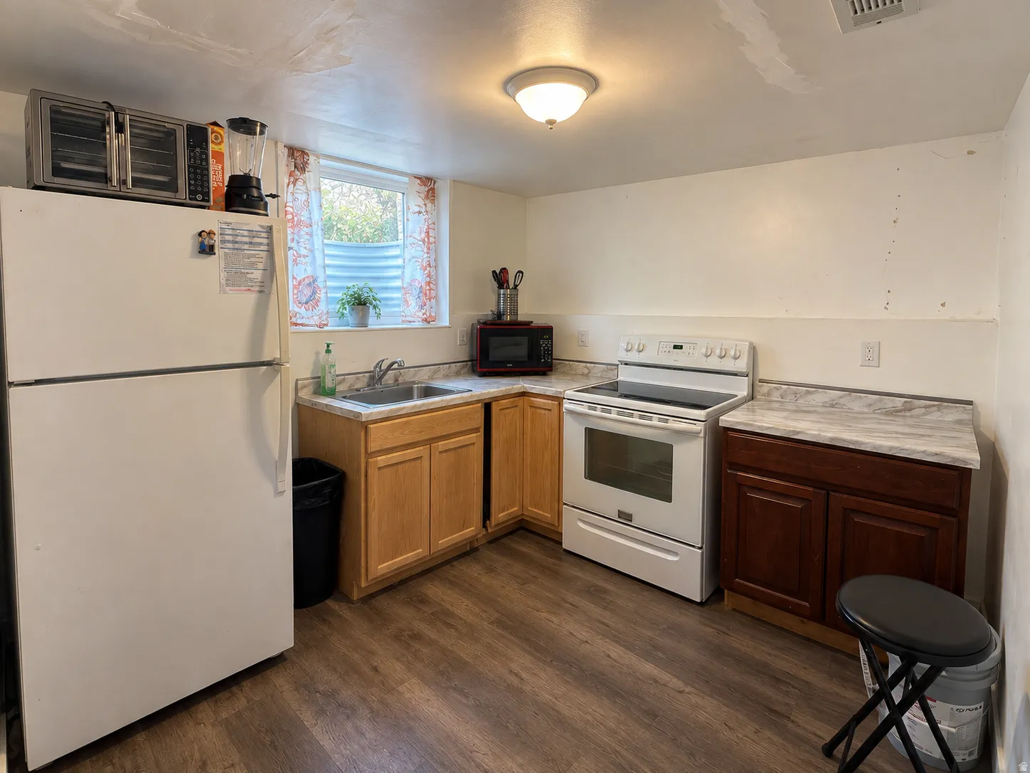 Kitchen featuring wood-finish flooring, two-tone cabinetry, a stainless steel sink, and light-toned countertops