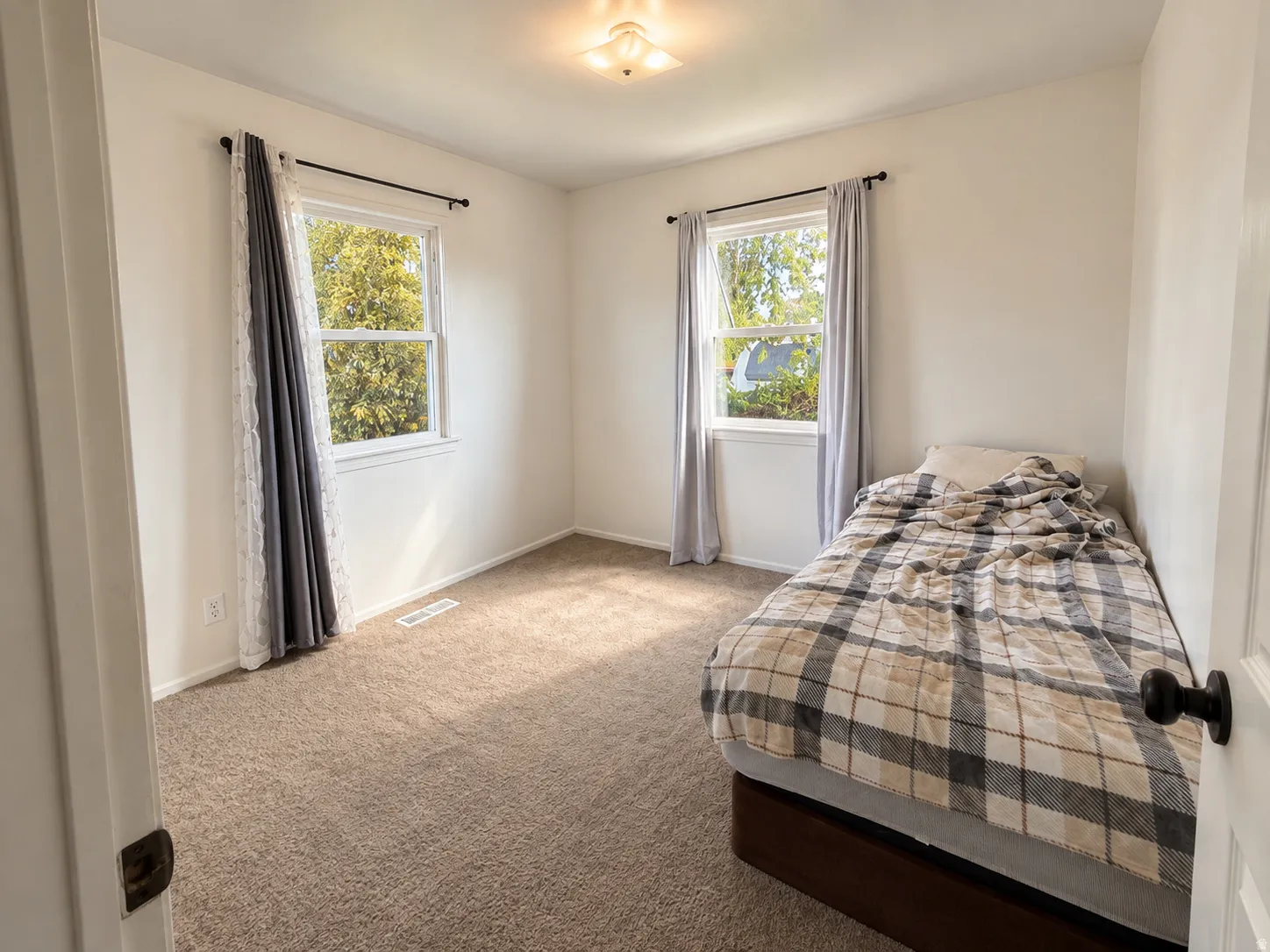 Neutral wall paint, two single-hung windows, and a flush-mount ceiling light fixture