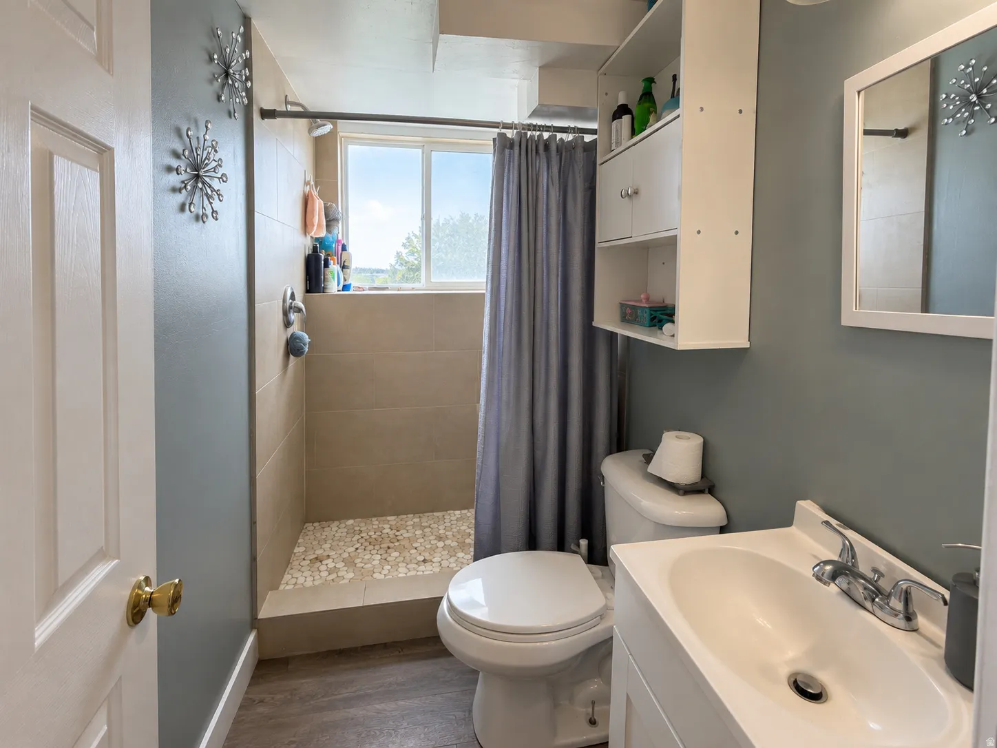 Walk-in shower with tiled walls and a pebble-finish floor