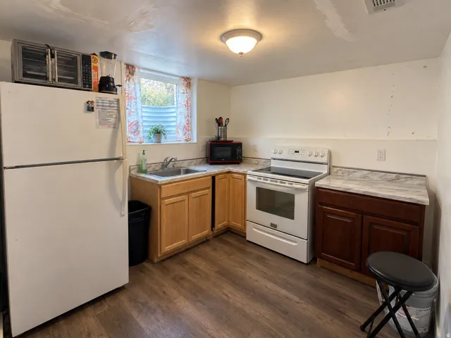 Kitchen featuring wood-finish flooring, two-tone cabinetry, a stainless steel sink, and light-toned countertops
