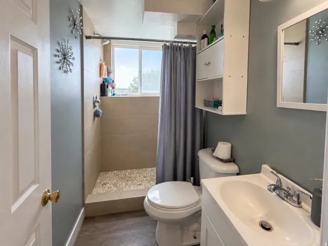 Walk-in shower with tiled walls and a pebble-finish floor