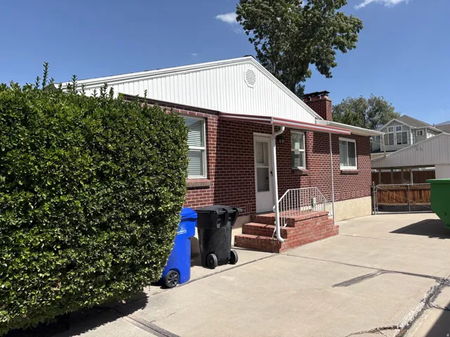 Brick exterior featuring white trim and a red awning