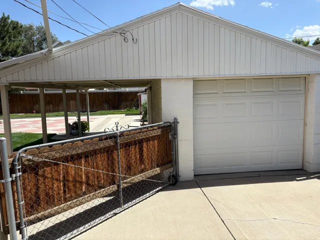 Attached carport and enclosed garage with a panel-style door