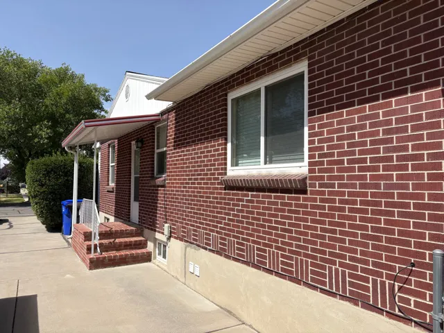 Brick exterior featuring a decorative band, white window frames, a covered entryway, and concrete steps