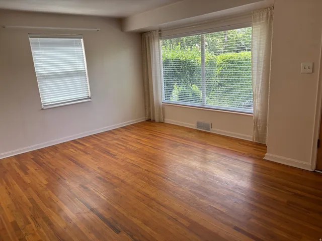 Hardwood flooring throughout, two large windows, window trim, and white walls