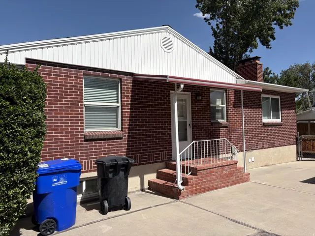 Brick exterior with white siding and a red awning