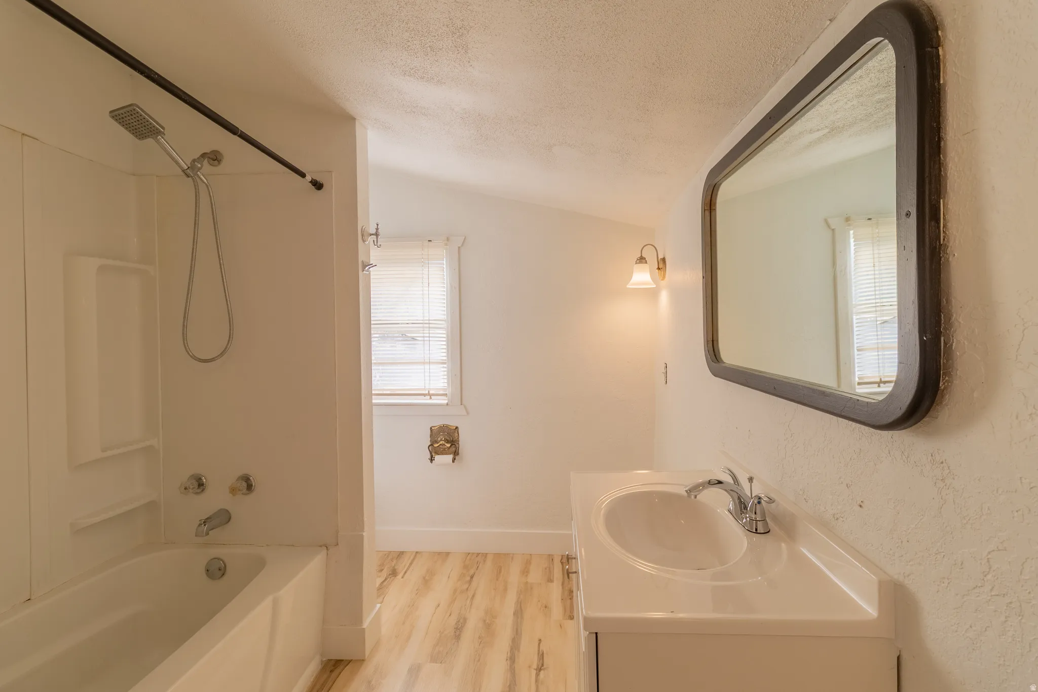 Bathroom featuring a white vanity with an integrated sink, chrome faucet, and wood-finish flooring