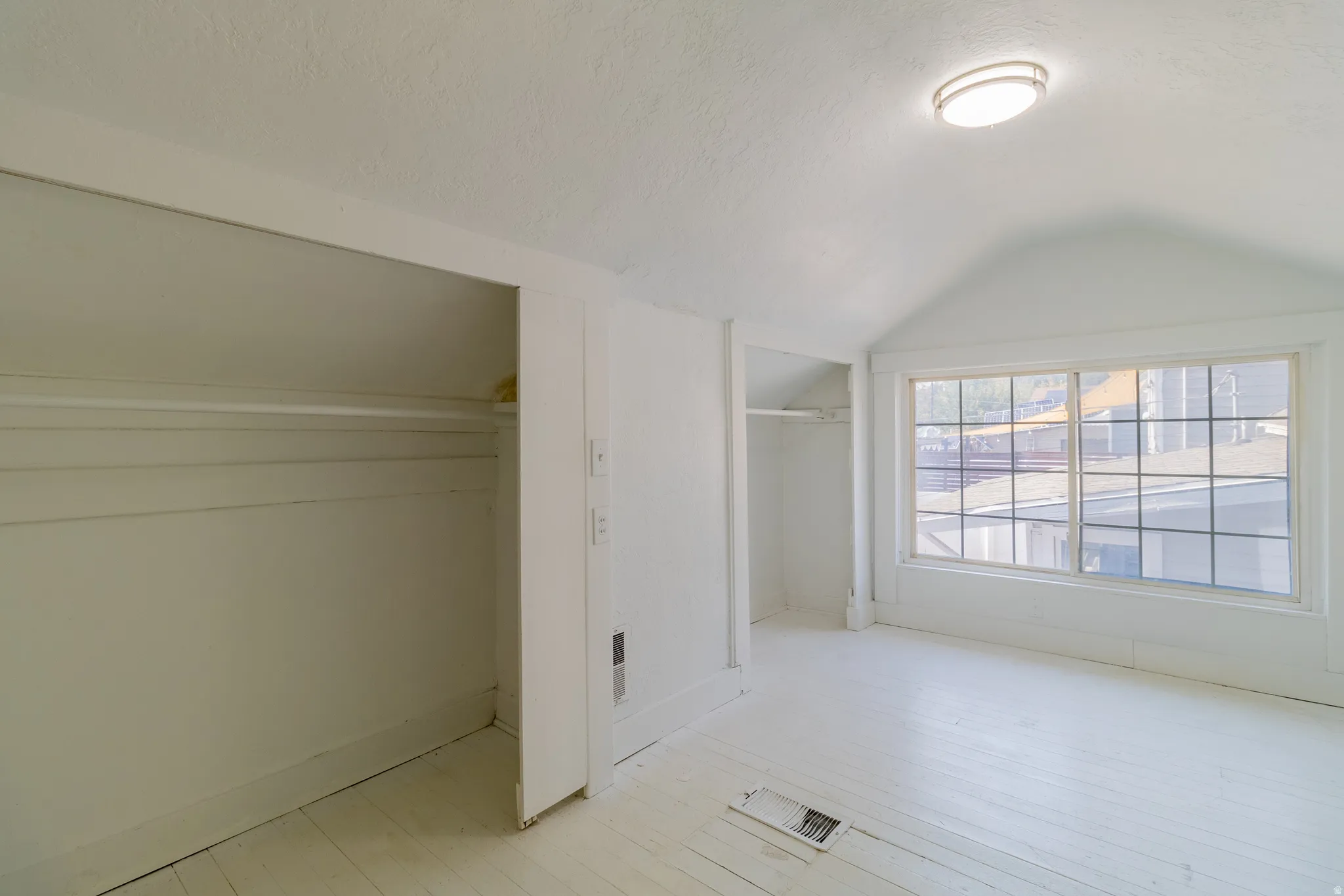 White plank flooring, recessed shelving, overhead flush-mount lighting, and a large multi-pane window