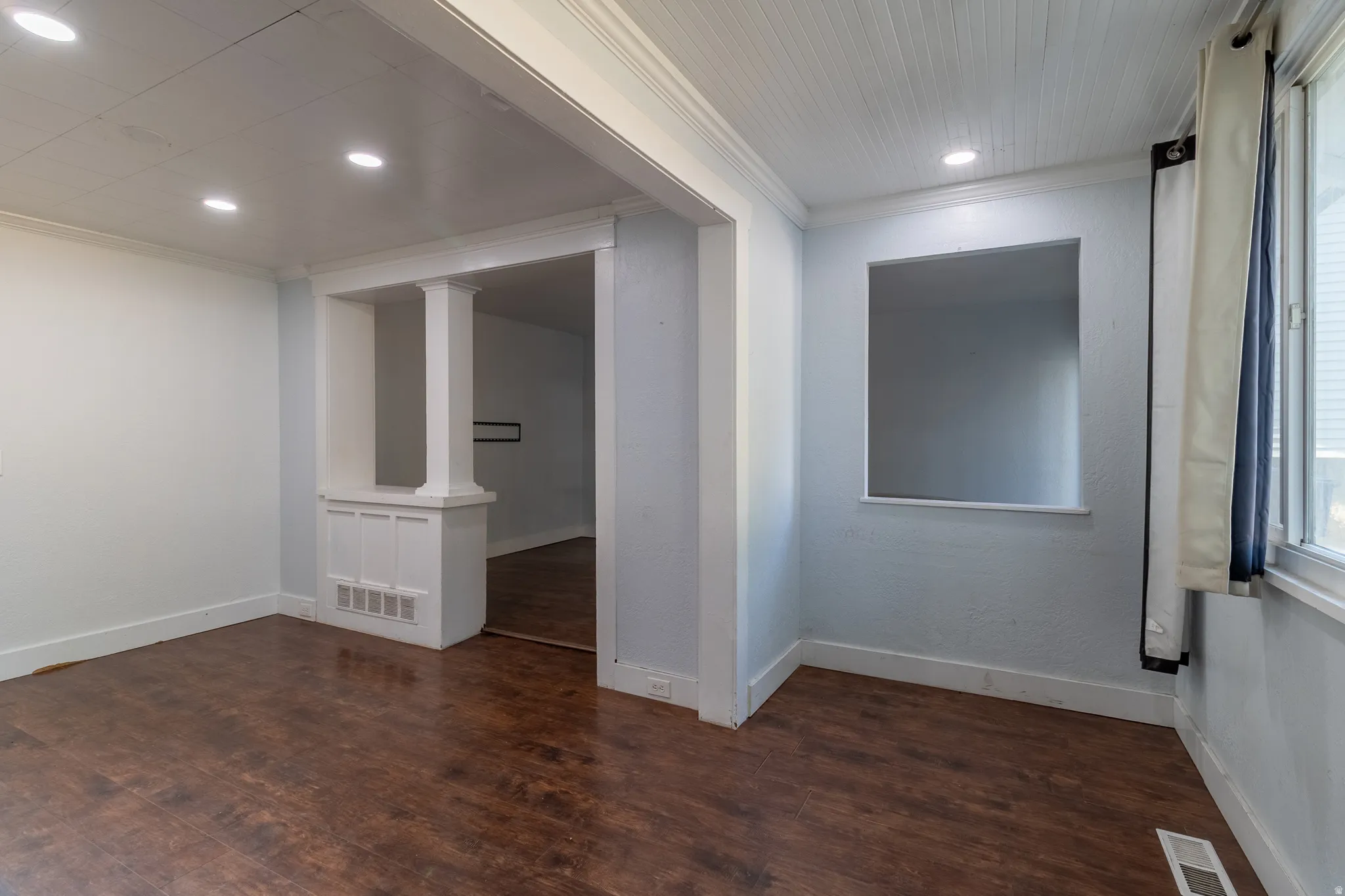 Wood-finish flooring throughout, recessed lighting, and a decorative column feature