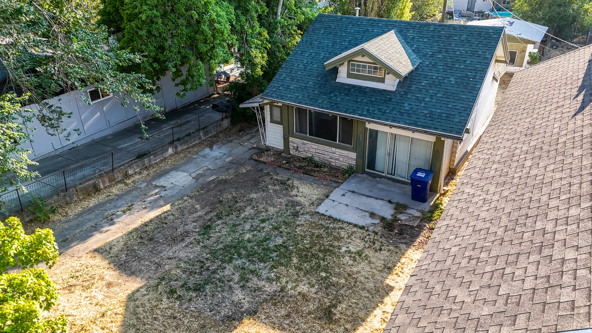 House featuring a dormer window, green shingle roof, sliding glass door, and an exterior patio