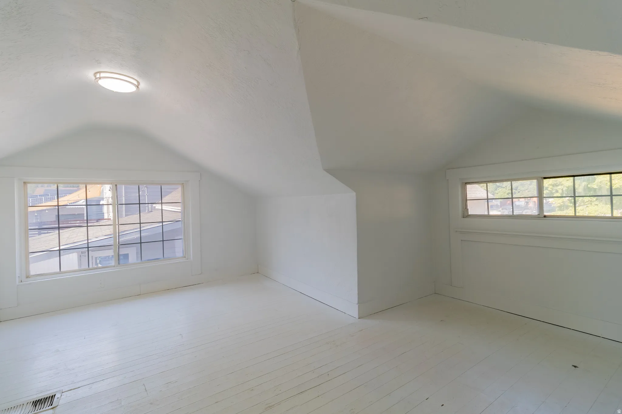 Sloped ceilings and white painted wood-finish flooring
