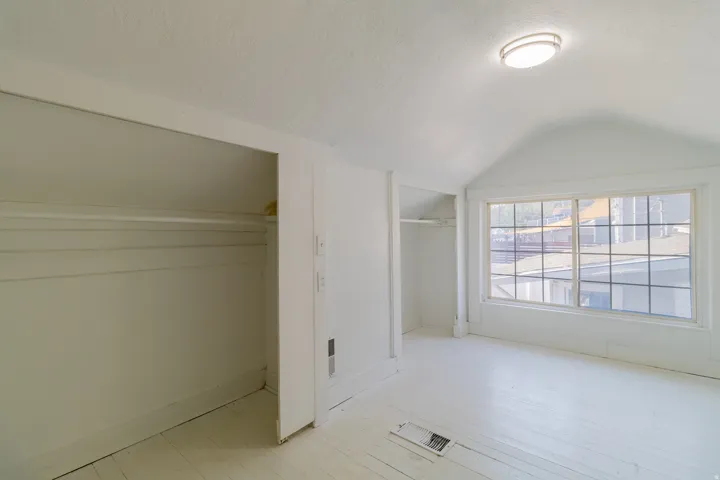 White plank flooring, recessed shelving, overhead flush-mount lighting, and a large multi-pane window